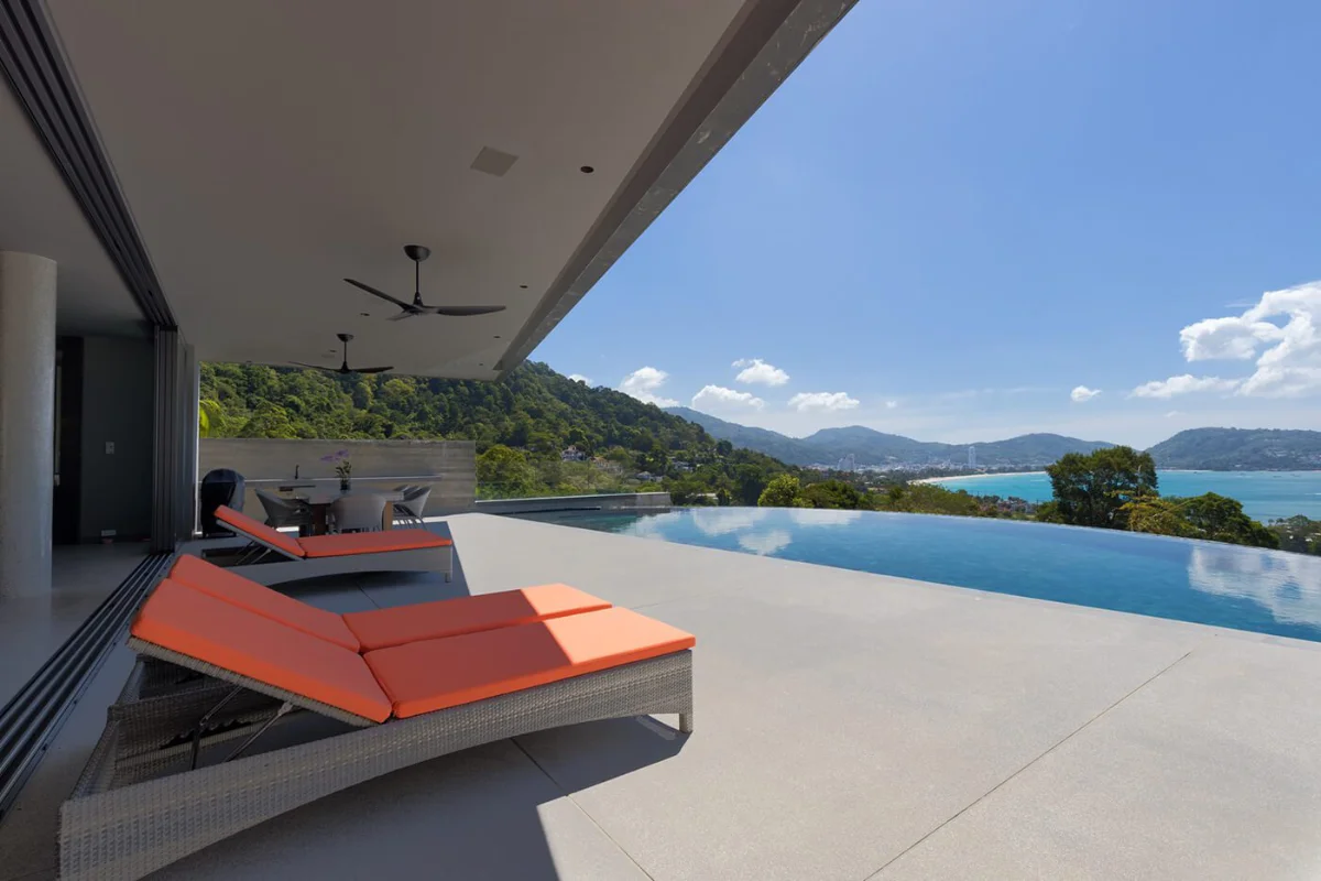 Rooftop saltwater infinity pool at Ocean Rock Kalim featuring orange sun loungers and panoramic bay views