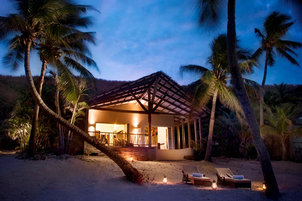 Evening exterior lighting of a 100 sqm beachfront villa at Tadrai Island Resort on Mana Island Fiji with beach lounge chairs