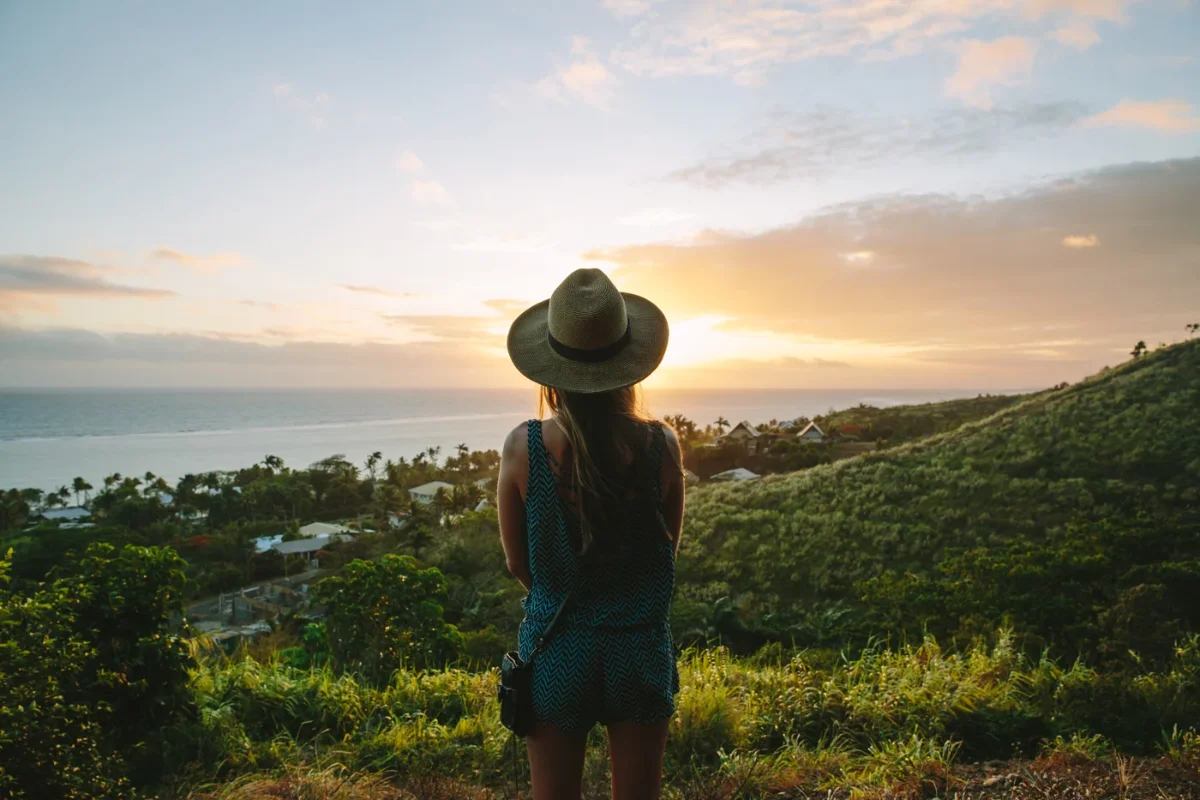 Woman with a hat standing on a hill overlooking Outrigger Fiji Beach Resort and the Pacific Ocean.