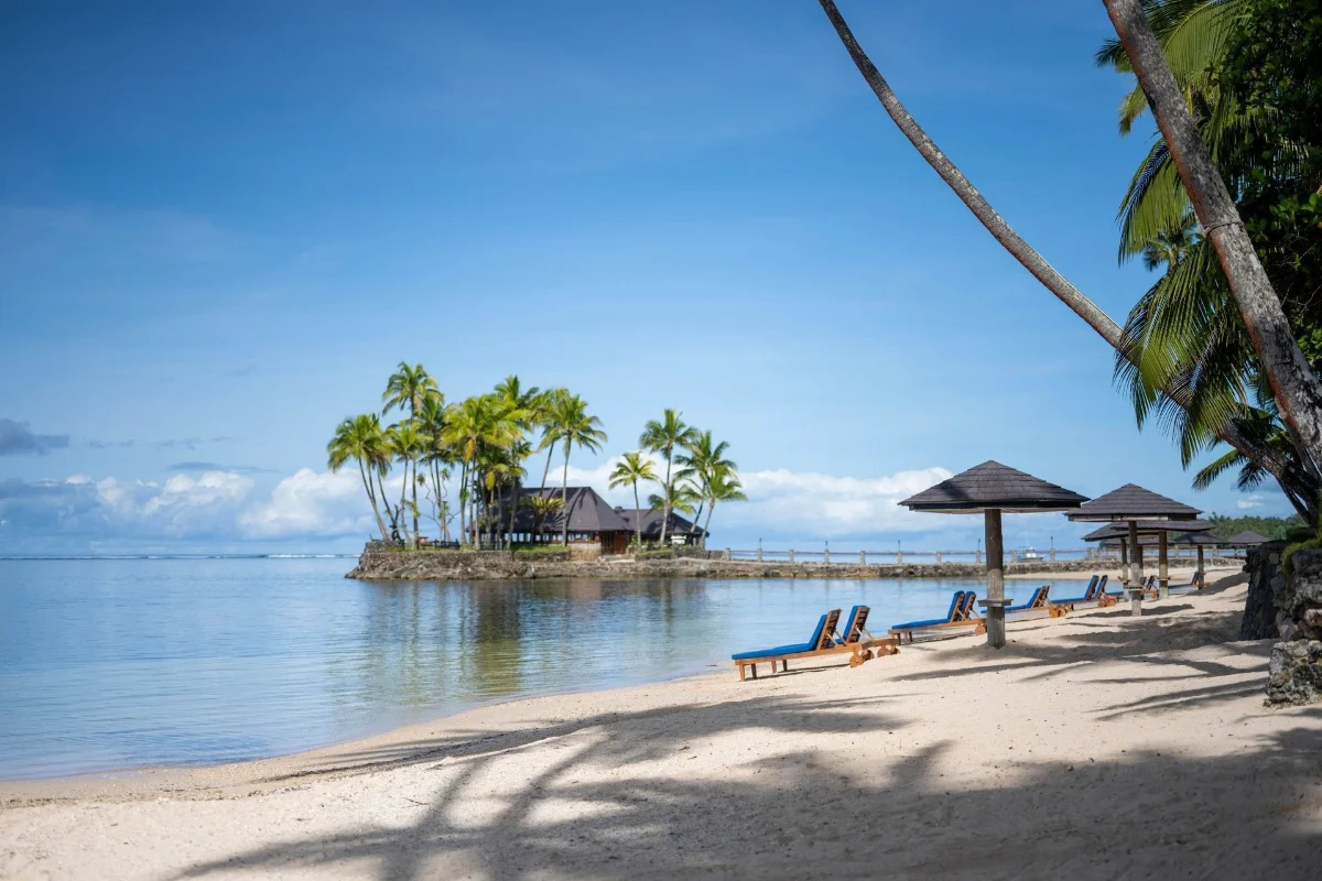 The Warwick Fiji private sandy beach with sun loungers and the offshore Wicked Walu restaurant islet