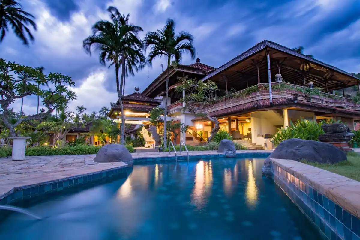 Outdoor swimming pool and traditional Balinese architecture main building at Puri Bagus Candidasa resort.
