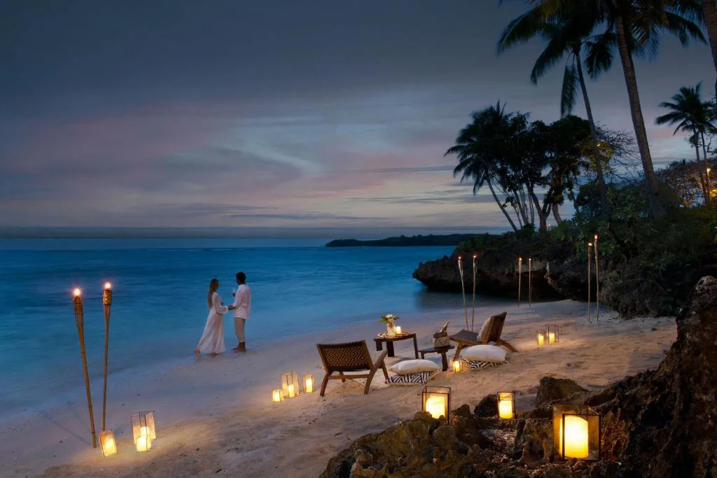 Couple standing on the private beach at Shangri-La Yanuca Island Fiji during evening candlelight setup