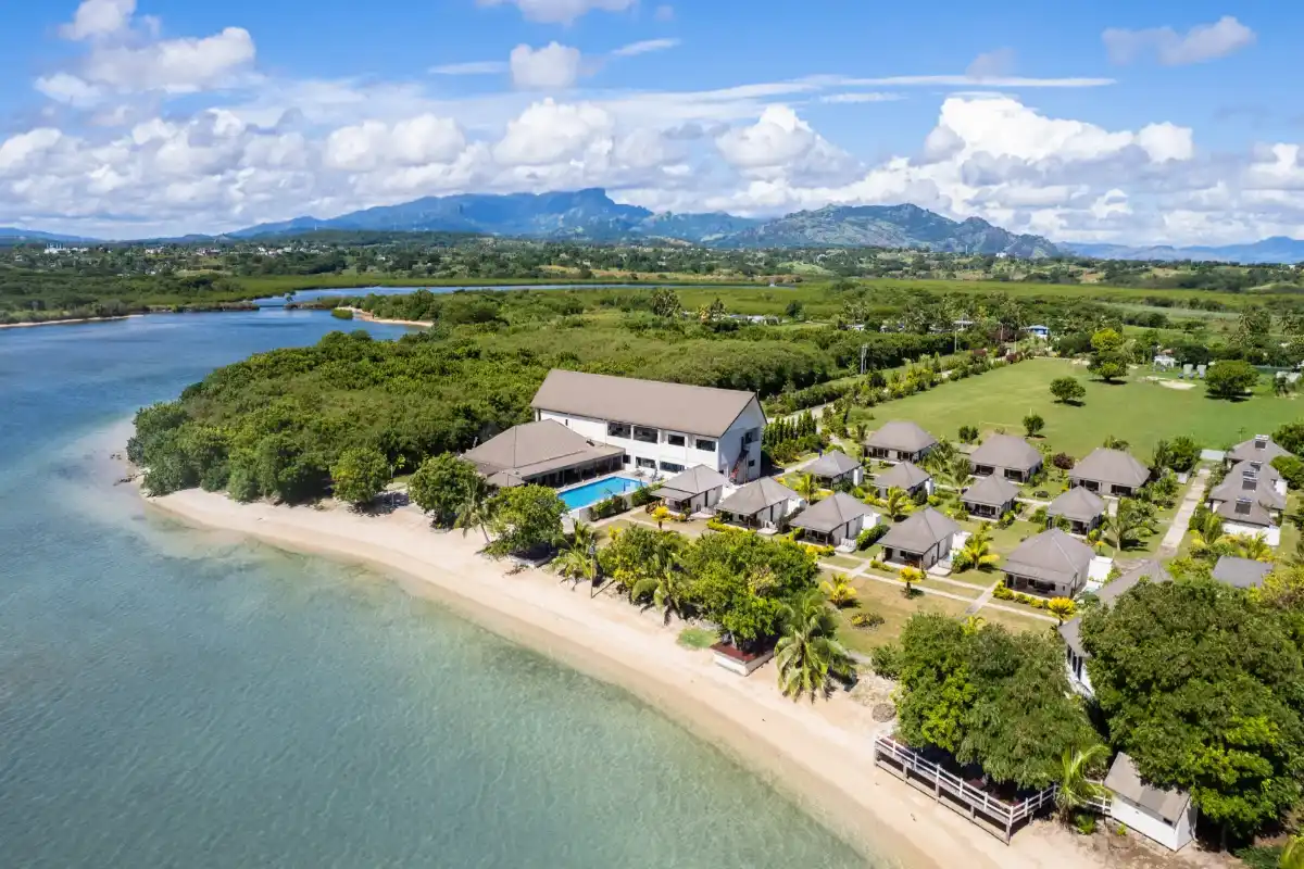 Aerial view of beachfront bungalows, main building, and outdoor swimming pool at Landers Bay Resort & Spa in Lautoka, Fiji.