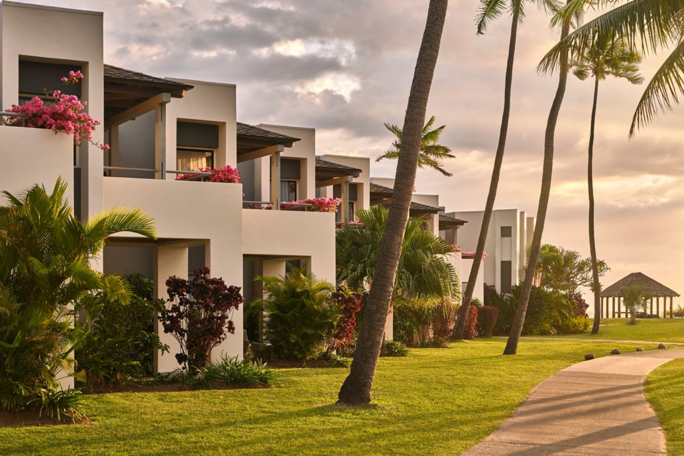 Exterior view of room blocks with balconies, coconut palm trees, and garden path at Sheraton Fiji Golf & Beach Resort on Denarau Island.