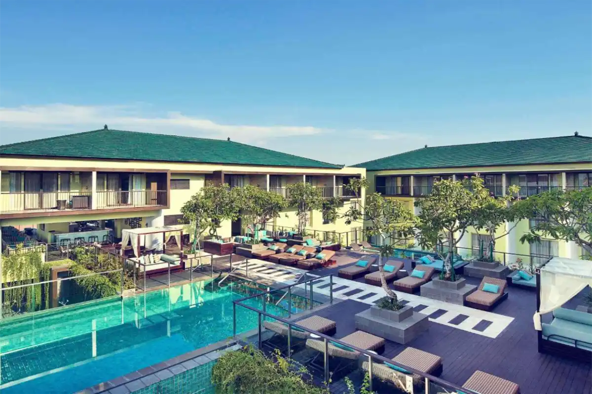 Outdoor swimming pool, lounge chairs, and balcony rooms at Mercure Bali Legian