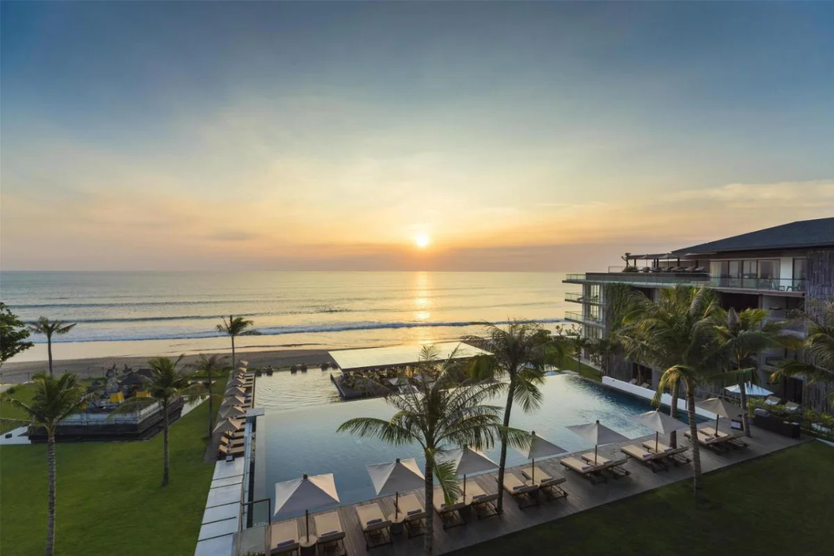 Alila Seminyak Bali beachfront infinity pool with sun loungers and Petitenget Beach sunset view