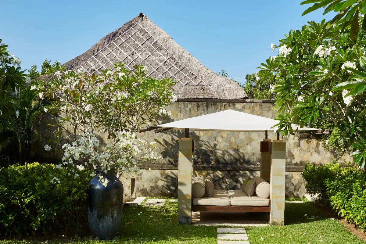 Outdoor relaxation gazebo with sunshade and traditional Balinese thatched roof in the private garden of Aman Villas at Nusa Dua.