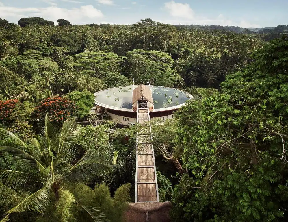 Aerial view of Four Seasons Resort Bali at Sayan wooden suspension bridge entrance and circular lotus pond in Ubud jungle