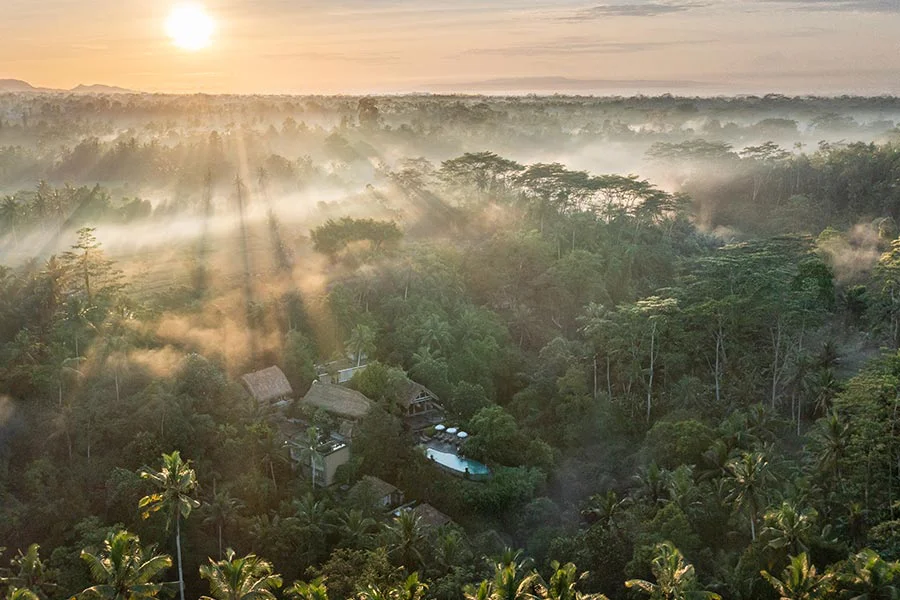 Aerial view of private pool villas and infinity pool surrounded by Karangasem jungle at The Kayon Gangga Resort.