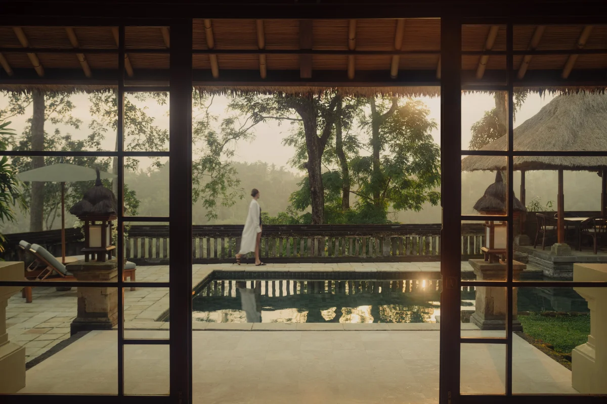 A guest walking on the secluded terrace of Amandari Ubud, showcasing the private pool and traditional Balinese pavilion overlooking the lush Ayung River Valley at sunset.