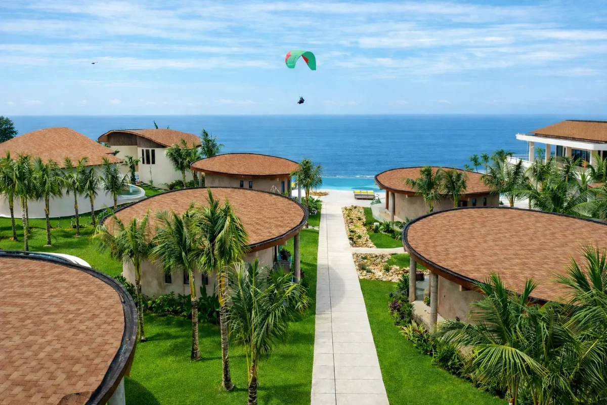 Aerial view of VANARA Resort's infinity pool overlooking the ocean, framed by tropical villas and palm trees, Bali vacation experience.
