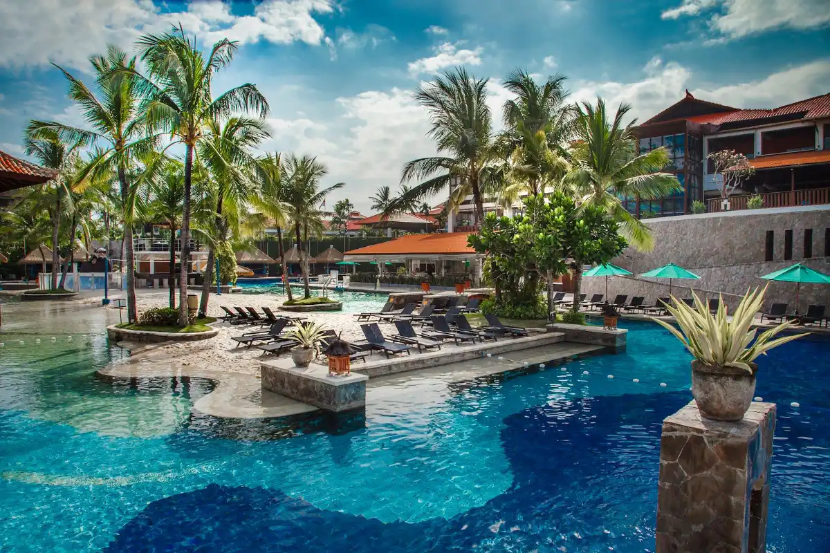 Hard Rock Hotel Bali main swimming pool with sand island, sun loungers and palm trees in Kuta