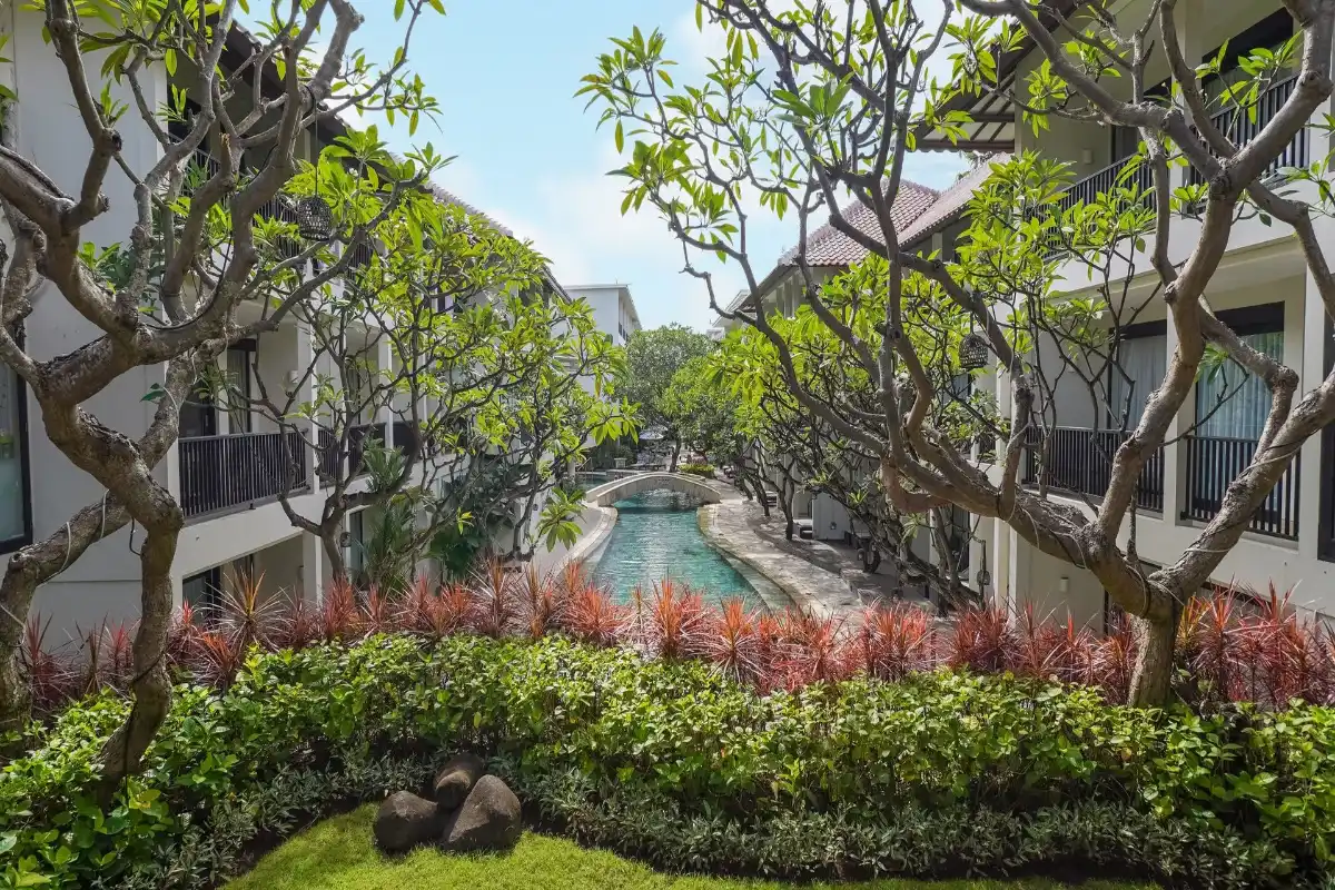 An interior courtyard view of Away Bali Legian Camakila showing the unique river pool with rooms featuring balconies.