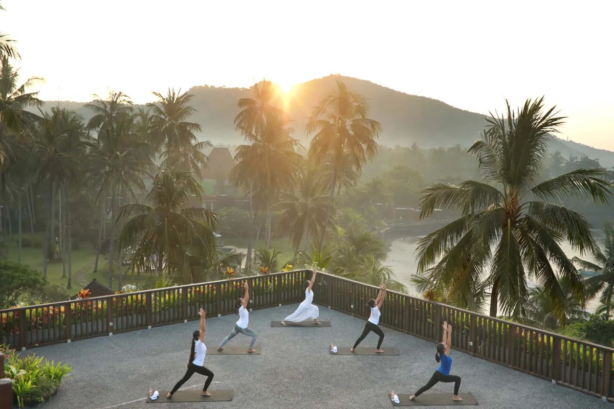 Group yoga session at sunrise on the outdoor yoga deck at Candi Beach Resort & Spa in Manggis, Bali.