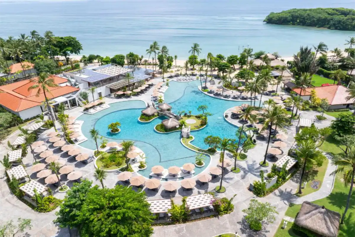 Aerial view of the main outdoor lagoon pool, sun loungers, and beachfront coastline at Paradisus by Meliá Bali in Nusa Dua.