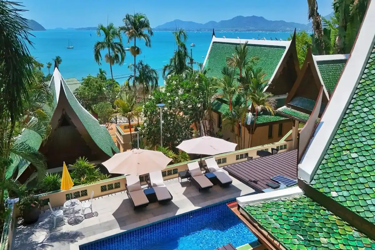 A pool terrace and sun loungers at D Villa Phuket, a traditional Lanna-style luxury rental in Panwa Cape, overlooking the turquoise ocean and islands.Caption: At D Villa Phuket, the traditional Lanna architectural aesthetic blends seamlessly with panoramic turquoise ocean views from this Panwa Cape terrace. Relax by your private pool and immerse yourself in Thailand's tranquil atmosphere.