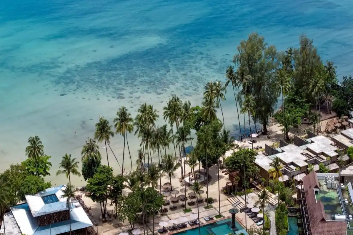 Aerial view of Dinso Resort & Villas Phuket beachfront area, palm trees, and outdoor swimming pool near Patong Beach.