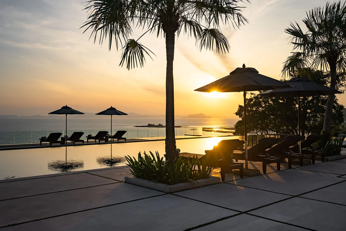 Ocean-facing infinity pool at Villa Sawarin Phuket during sunset, with sun loungers.