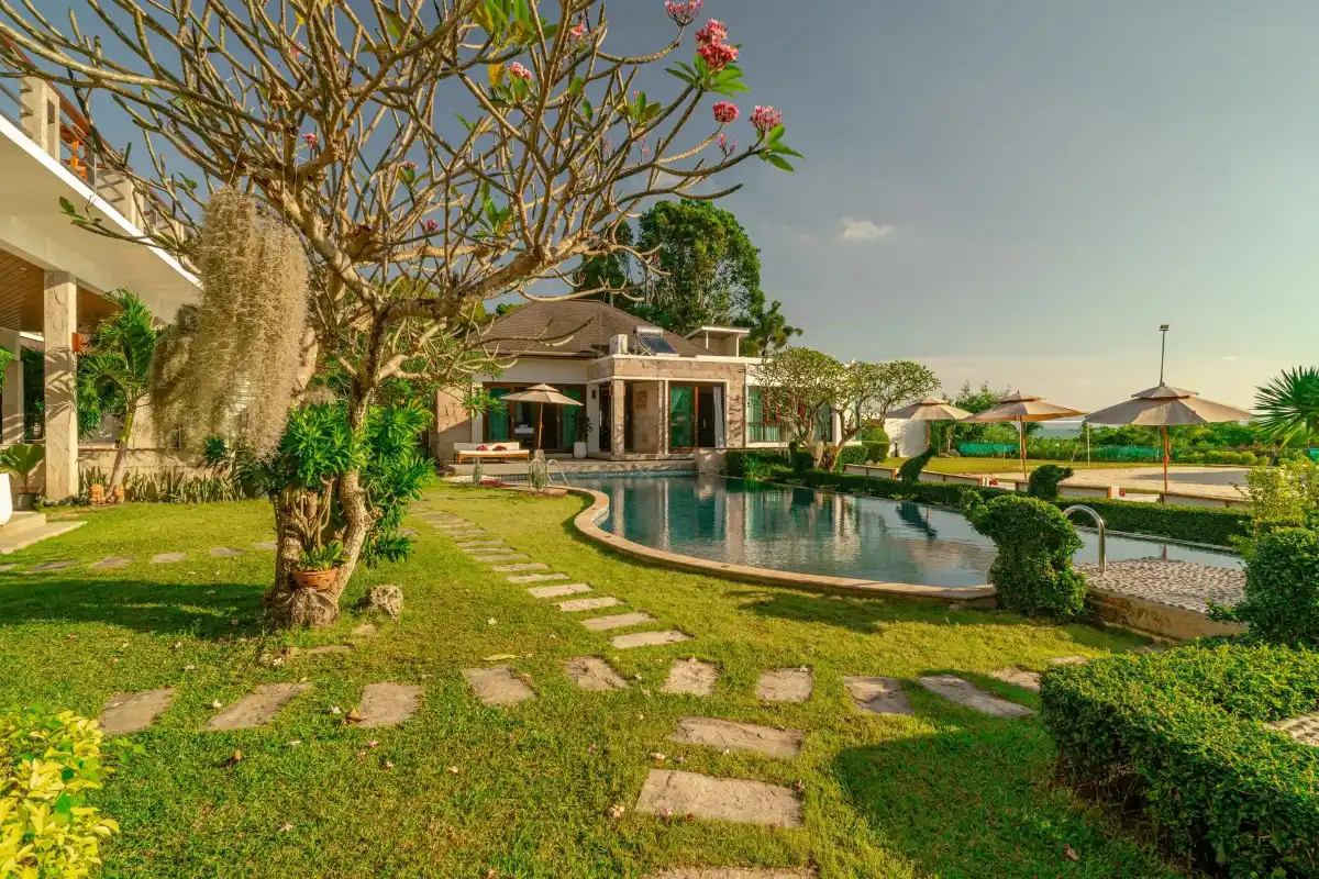 Private outdoor swimming pool, lush green garden, and beach volleyball court at Kiri Anda Villa Phuket