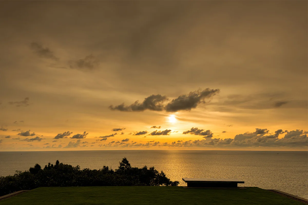 The golden sun setting over the Andaman Sea as seen from a private cliffside terrace at Paresa Resort Phuket, Kamala.