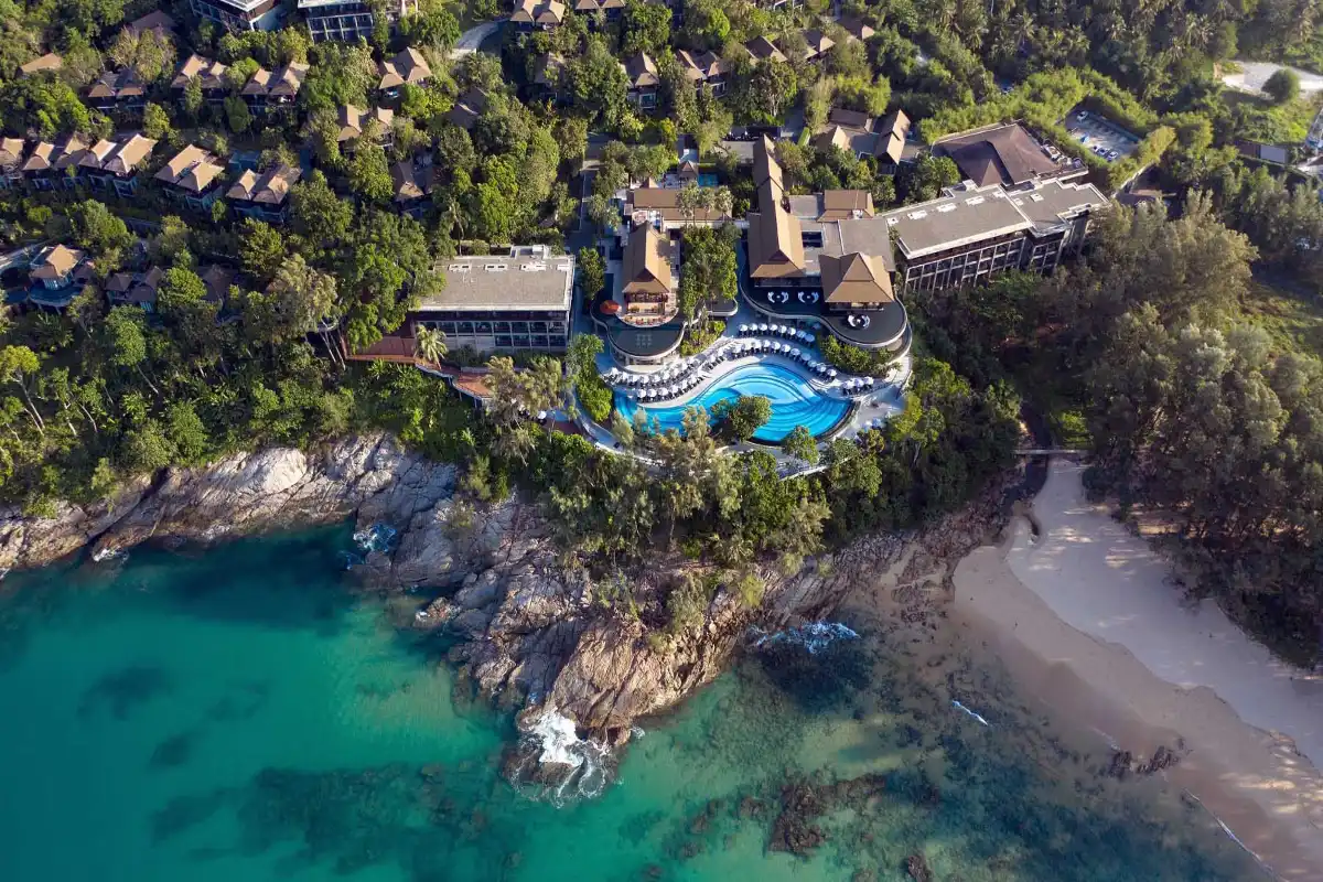 Aerial view of Pullman Phuket Arcadia Naithon Beach resort featuring the main outdoor pool, rocky coastline, and surrounding tropical forest.