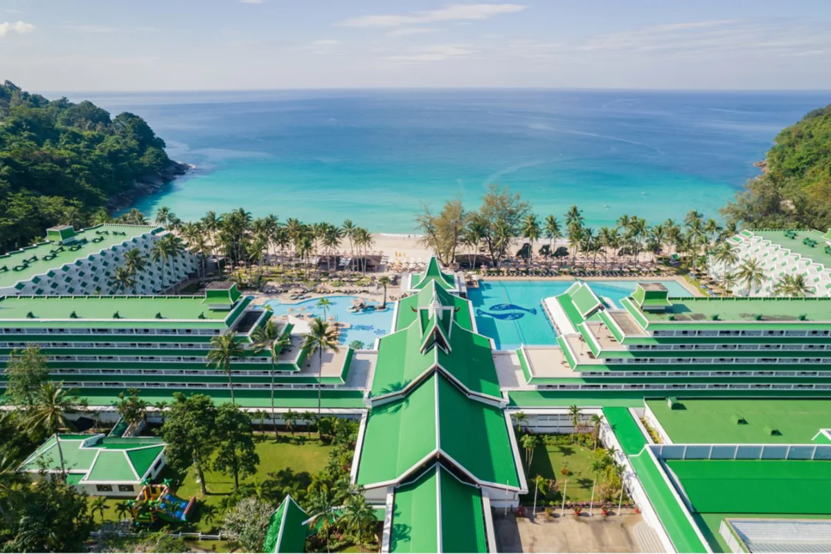 Aerial view of Le Méridien Phuket Beach Resort featuring green-roofed buildings, outdoor pools, and direct access to Karon Noi Beach.