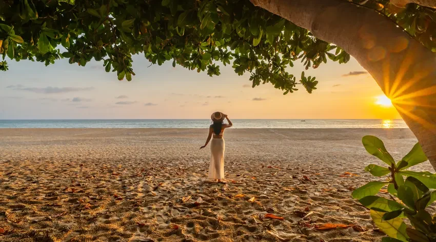 Female guest walking on Karon Beach shore at sunset directly in front of Centara Grand Beach Resort Phuket.