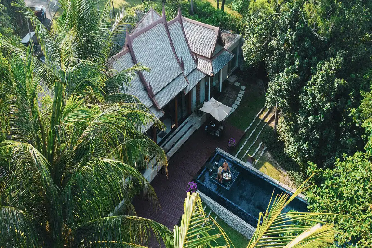 Aerial view of Banyan Tree Phuket traditional Thai pool villa featuring a private swimming pool, sun deck, and floating breakfast setup among tropical palm trees.